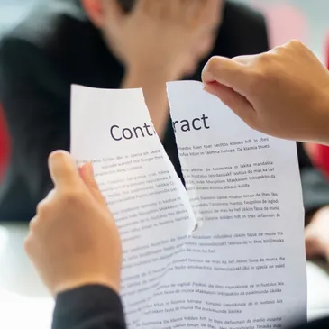 A picture of the hands of a person ripping apart a contract