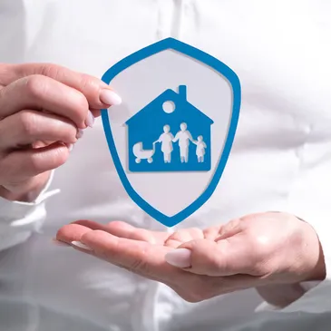 A picture of the hands of a person showing a plastic shield with a drawing of a family inside a home